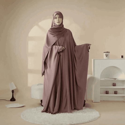 Woman wearing 5 piece satin abaya set in mauve color by Fabaya UK standing in stylish room