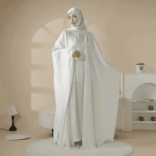 Elegant white 5 piece satin abaya set by Fabaya UK worn by woman in modern beige room