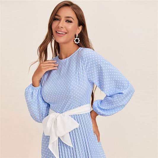 Woman wearing a blue polka dot abaya dress with long puff sleeves and white waist tie