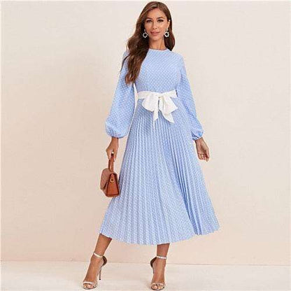 Woman wearing a blue polka dot abaya dress with long sleeves and white waist bow belt