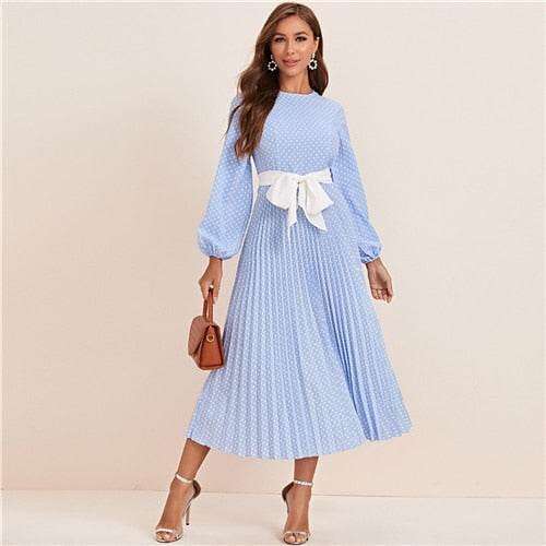 Woman wearing a blue polka dot abaya dress with long sleeves and white waist bow belt