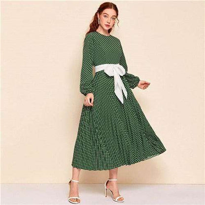 Woman wearing a green polka dot abaya dress with long sleeves and a white waist bow belt