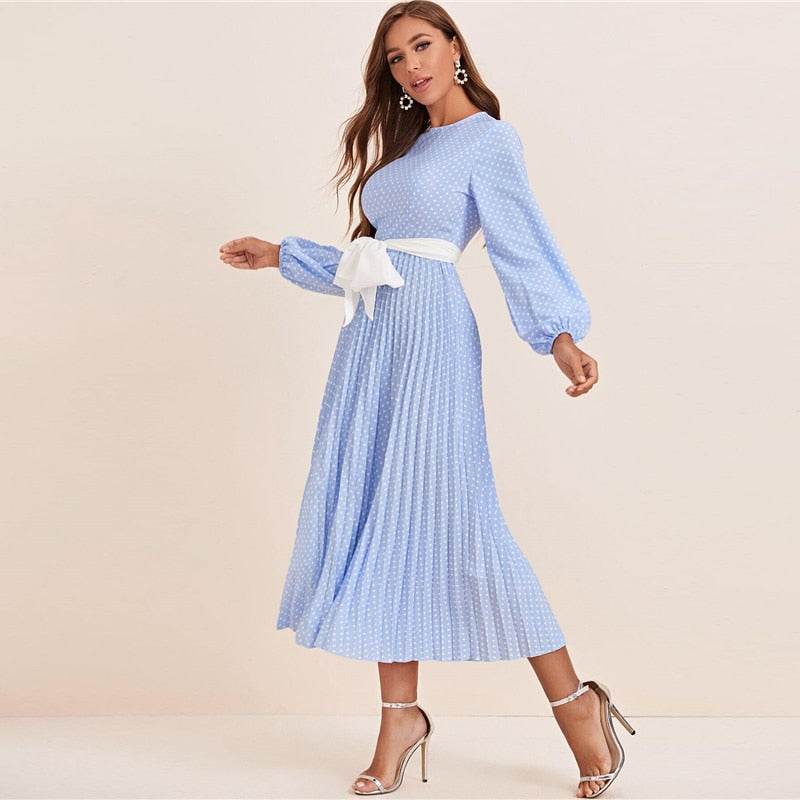 Woman wearing a blue polka dot abaya dress with long sleeves and a white waist tie belt