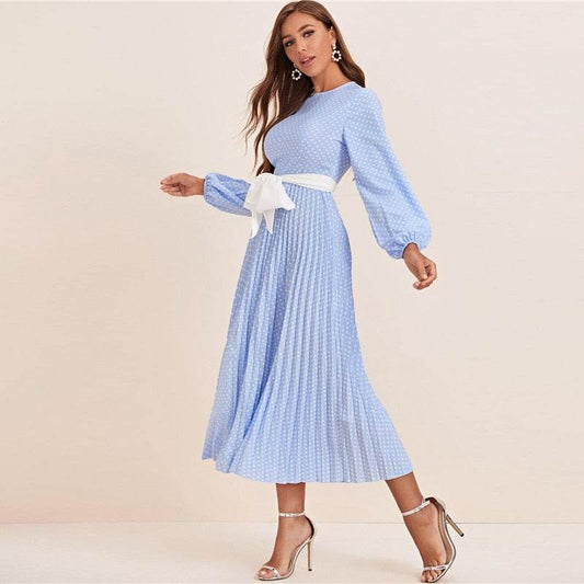 Woman wearing a blue polka dot abaya dress with long sleeves and a white waist tie belt