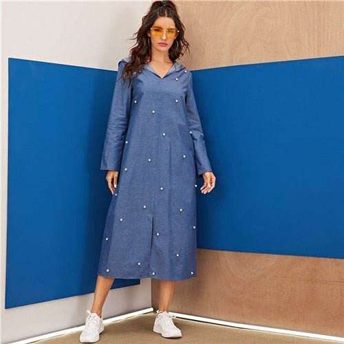 Woman wearing a long denim hoodie dress for women with pearl embellishments and white sneakers
