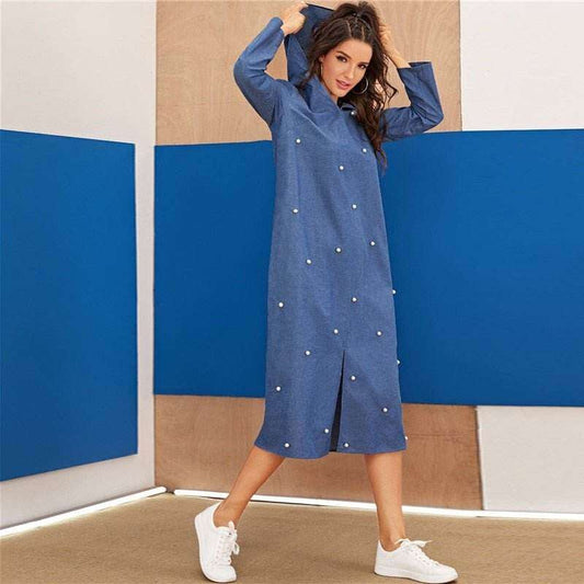 Woman wearing a blue denim hoodie dress for women with pearl embellishments and white sneakers