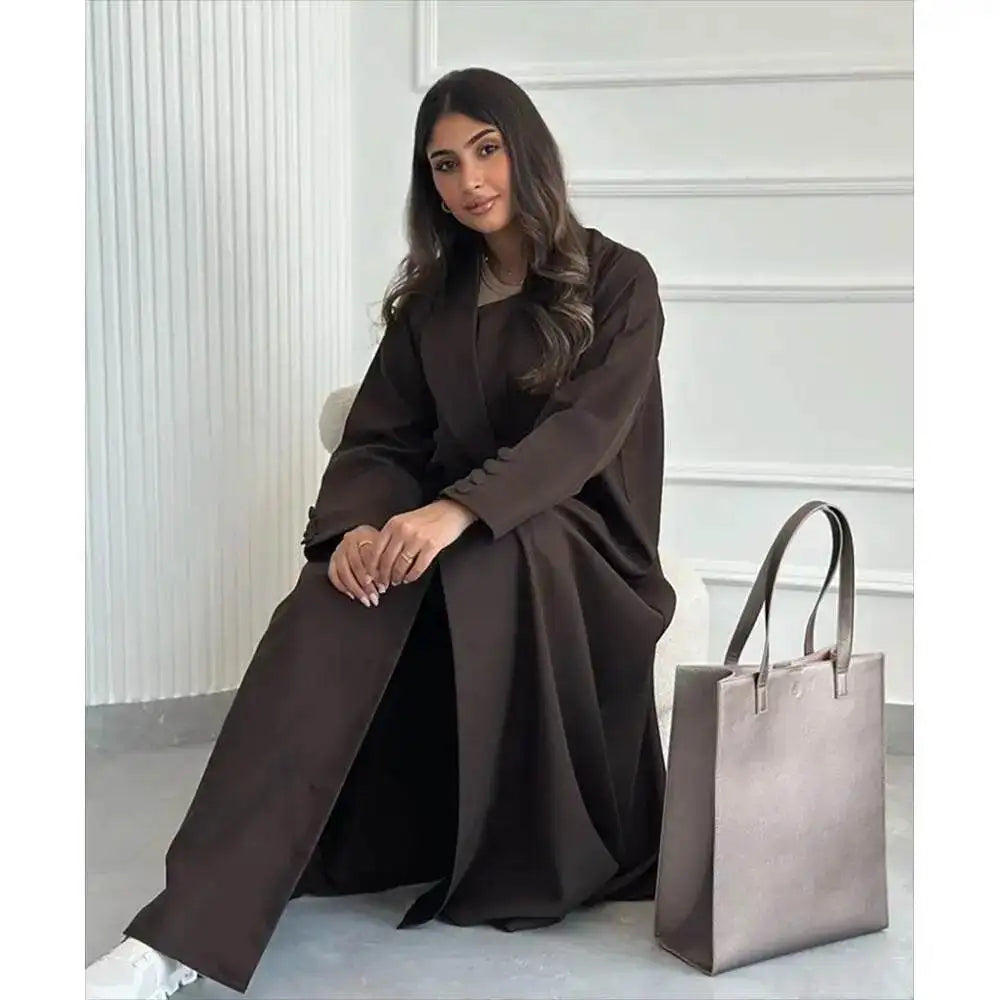 Fabaya UK brown abaya jacket for women worn by a seated woman with long hair and paired with a large gray handbag