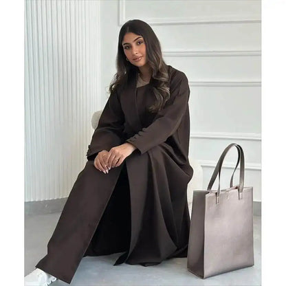Fabaya UK brown abaya jacket for women worn by a seated woman with long hair and paired with a large gray handbag