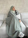 Woman wearing a Fabaya UK luxury linen abaya in light gray sitting on a modern sofa