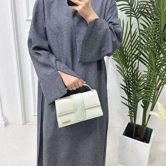 Fabaya UK luxury linen abaya in gray with wide sleeves, shown with a white handbag