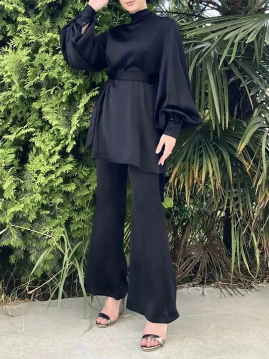 Woman wearing a shiny silky abaya set in black with puffed sleeves and wide-leg pants outdoors