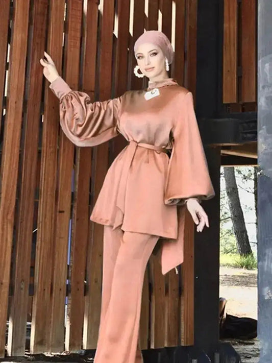 Woman wearing a shiny silky abaya set in a soft peach color with balloon sleeves and matching pants