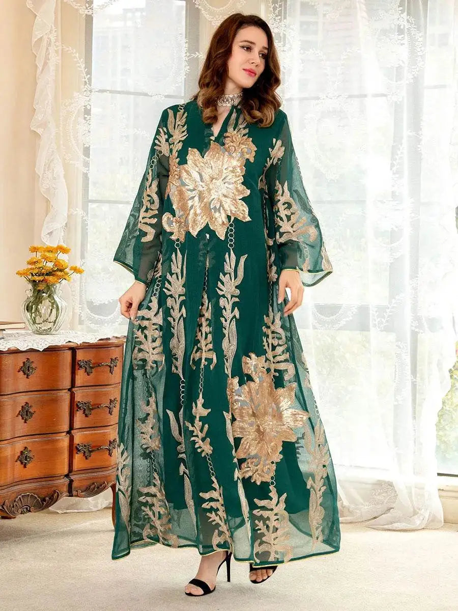 Woman wearing a green Moroccan embroidered abaya dress with intricate gold floral designs standing indoors