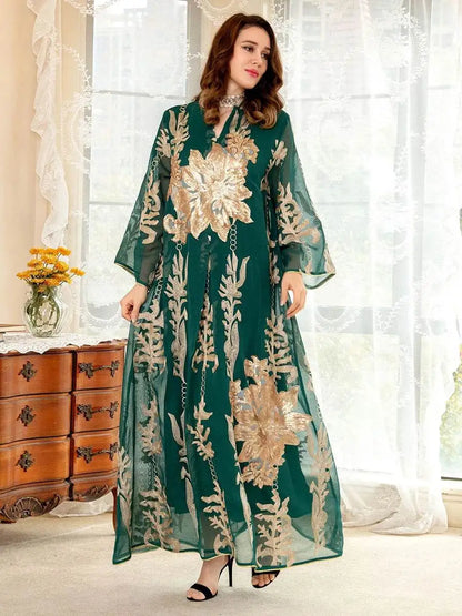 Woman wearing a green Moroccan embroidered abaya dress with intricate gold floral designs standing indoors