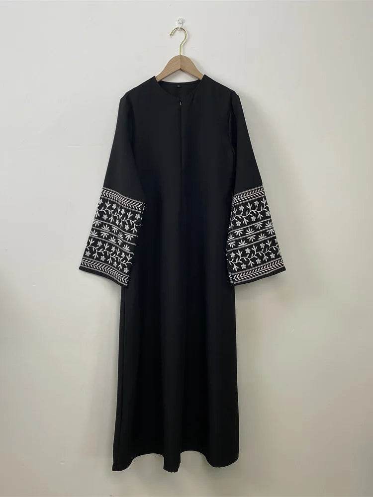 Black stylish muslim abaya for women with white embroidered wide sleeves hanging on wooden hanger