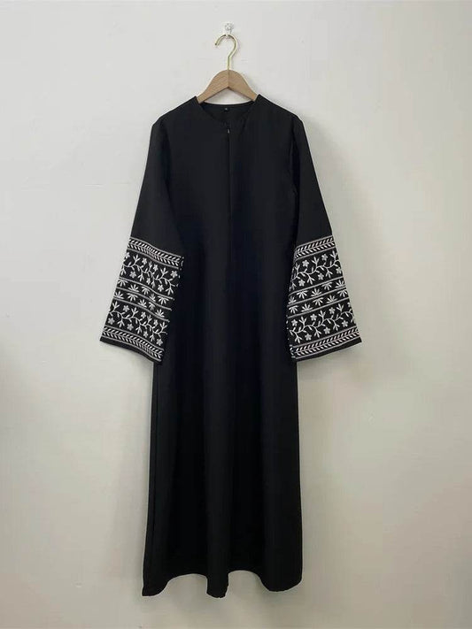 Black stylish muslim abaya for women with white embroidered wide sleeves hanging on wooden hanger
