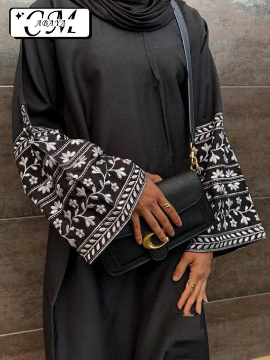 Stylish muslim abaya for women in black with detailed white embroidered sleeves and black handbag