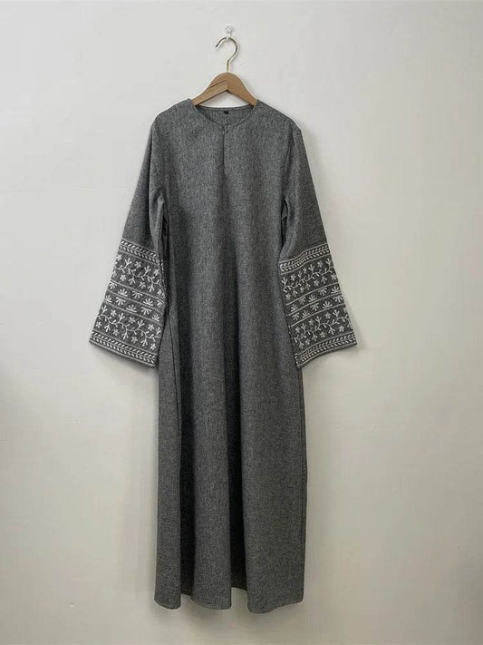 Stylish muslim abaya for women in gray with embroidered sleeves hanging on wooden hanger